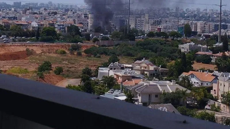 বিস্ফোরণের ধোঁয়া ও কালো ধোঁয়া উড়ছে, শহরের পেছনে আকাশে ধোঁয়া।. Channel i News - চ্যানেল আই নিউজ