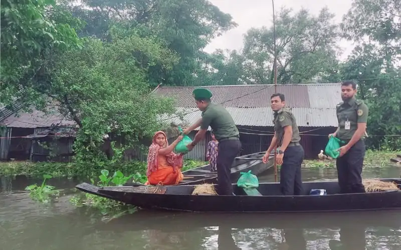 বন্যার্তদের সাহায্য করতে আনসার সদস্যরা নদীতে নৌকায় দাঁড়িয়ে. Channel i News - চ্যানেল আই নিউজ