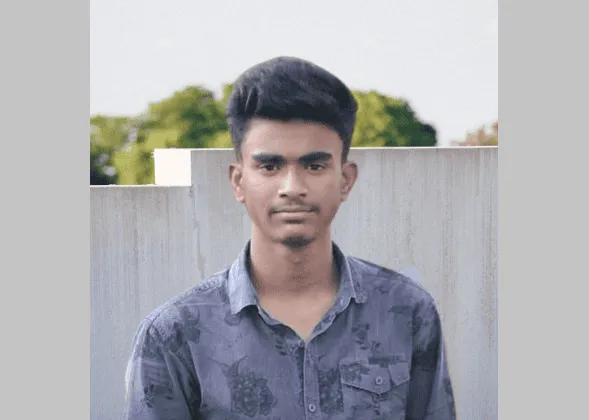 Young man standing outdoors with a neutral expression, wearing a blue shirt. Channel i News - চ্যানেল আই নিউজ