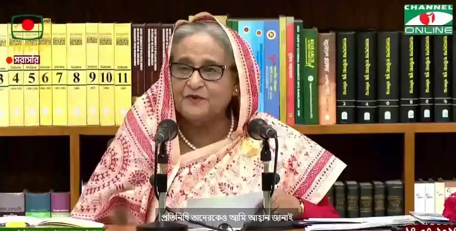 প্রধানমন্ত্রী ভাষণ দিচ্ছেন, পেছনে বইয়ের তাক।. Channel i News - চ্যানেল আই নিউজ