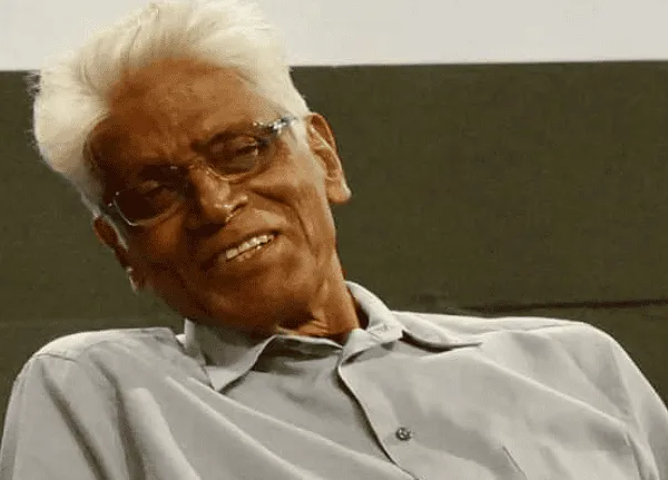 বয়সী ব্যক্তি হাস্যোজ্জ্বল মুখে বসে আছেন, চশমা পরা।. Channel i News - চ্যানেল আই নিউজ