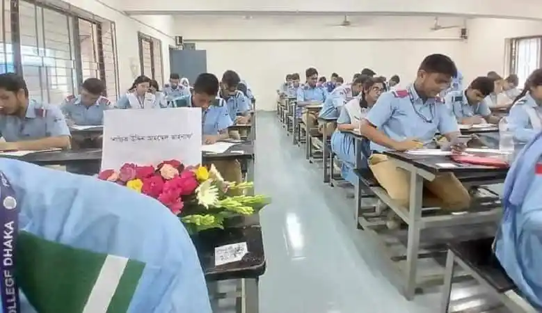 শিক্ষার্থীরা শ্রেণীকক্ষে পড়াশোনা করছে, পাশে ফুলের তোড়া রাখা. Channel i News - চ্যানেল আই নিউজ