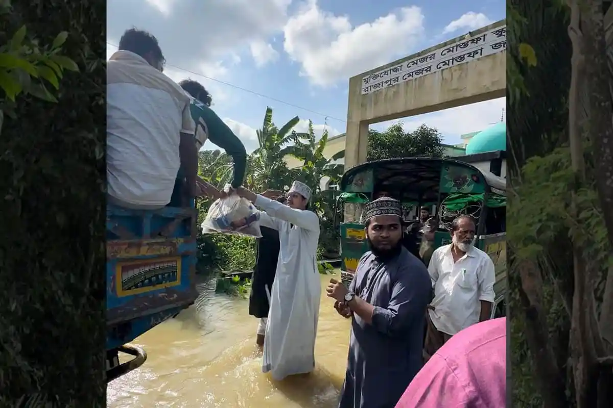 ত্রাণ বিতরণ কার্যক্রমে অংশগ্রহণকারী ব্যক্তিরা পানিতে দাঁড়িয়ে ত্রাণ সামগ্রী গ্রহণ করছেন. Channel i News - চ্যানেল আই নিউজ