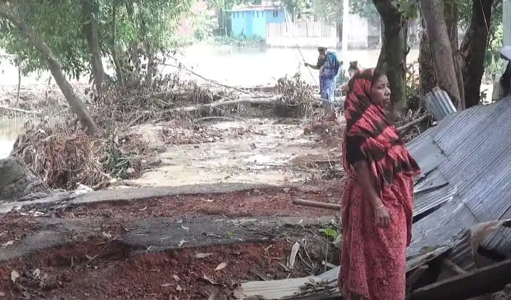 বন্যার কারণে ক্ষতিগ্রস্ত এলাকা, নারী ক্ষতিগ্রস্ত বাড়ির পাশে দাঁড়িয়ে. Channel i News - চ্যানেল আই নিউজ