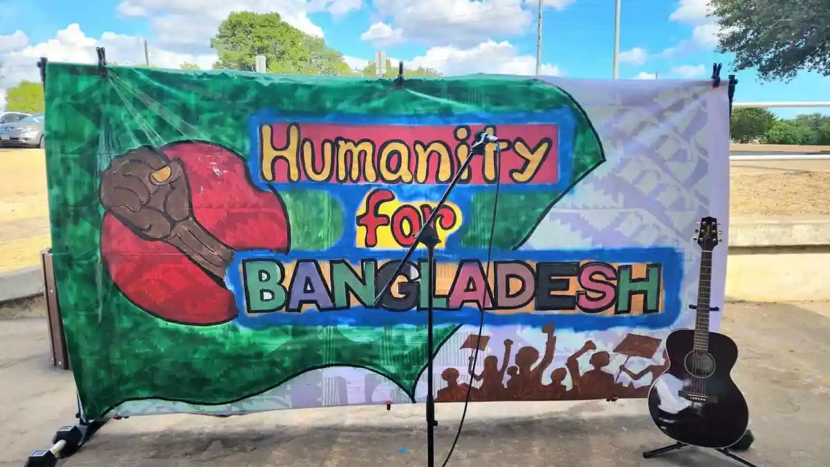 Colorful banner with 'Humanity for Bangladesh' message and guitar at outdoor event. Channel i News - চ্যানেল আই নিউজ