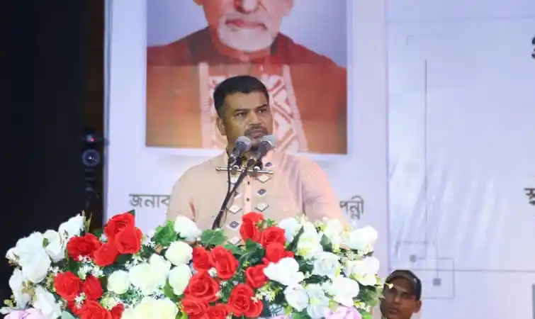 বাংলাদেশের রাজনৈতিক নেতা বক্তৃতা দিচ্ছেন, পেছনে বঙ্গবন্ধুর ছবি. Channel i News - চ্যানেল আই নিউজ