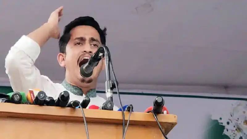 একজন সাংবাদিক বক্তৃতা দিচ্ছেন, পেছনে মাইক্রোফোন ও অন্যান্য সরঞ্জাম. Channel i News - চ্যানেল আই নিউজ