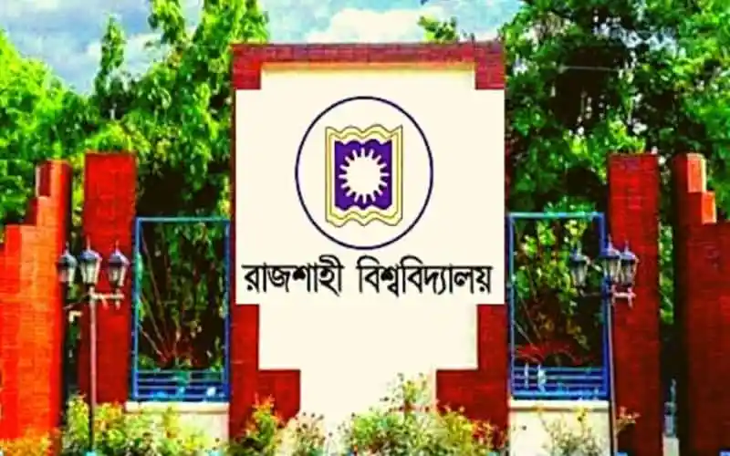 রাজশাহী বিশ্ববিদ্যালয়ের প্রধান গেটের ছবি, সবুজ গাছের পেছনে লাল ইটের দেয়াল. Channel i News - চ্যানেল আই নিউজ