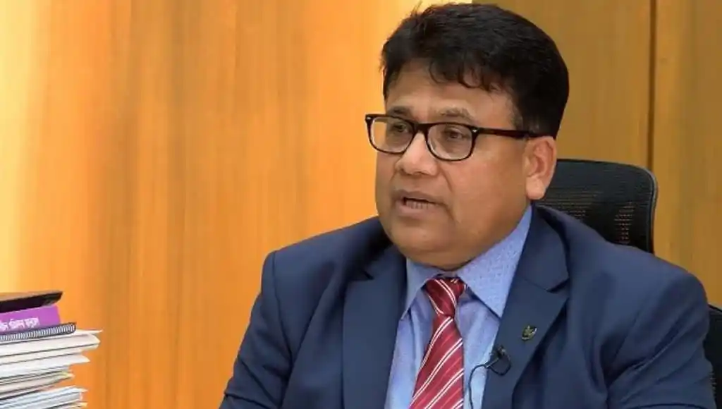 নির্বাচন কমিশন সচিব হেলালুদ্দীন সাক্ষাৎকারে বসে আছেন. Channel i News - চ্যানেল আই নিউজ