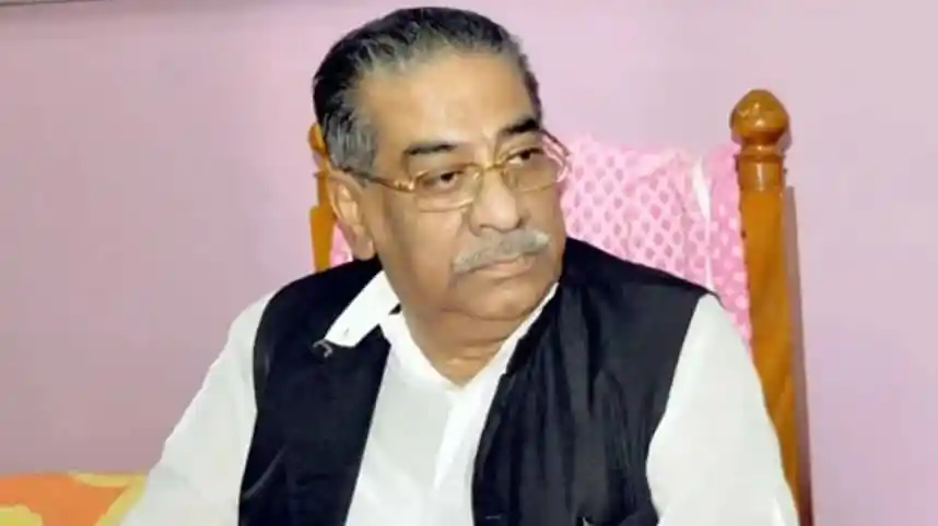 আবুল হাসানাত আবদুল্লাহ বসে থাকছেন, পেছনে হালকা গোলাপি দেয়াল. Channel i News - চ্যানেল আই নিউজ