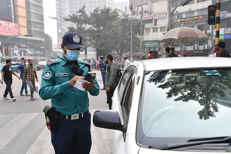Traffic police officer checking documents at busy intersection in Bangladesh. Channel i News - চ্যানেল আই নিউজ