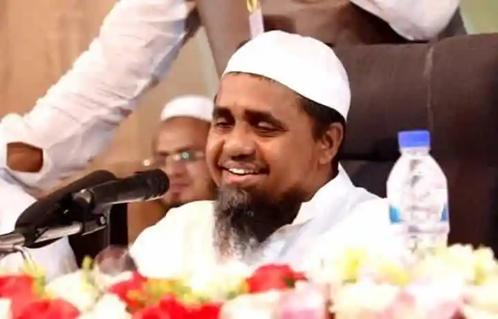 বায়তুল মোকাররমের নতুন খতিব আবদুল মালেকের ছবি, তিনি মঞ্চে বসে আছেন ও হাসছেন. Channel i News - চ্যানেল আই নিউজ