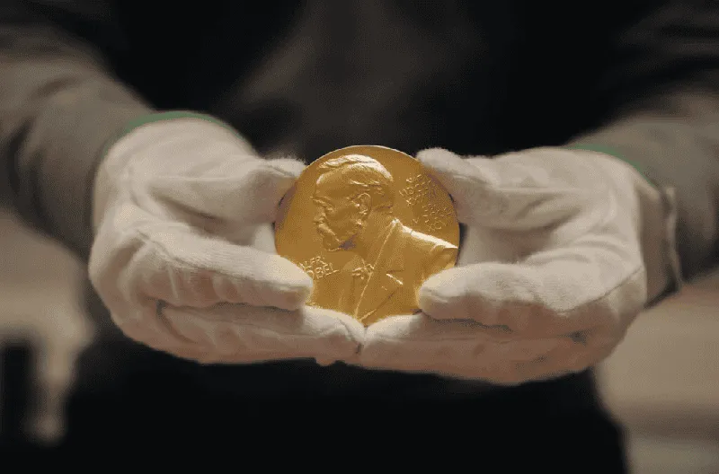নোবেল পুরস্কারপ্রাপ্ত সংস্থার স্বর্ণপদক হাতে ধরা. Channel i News - চ্যানেল আই নিউজ
