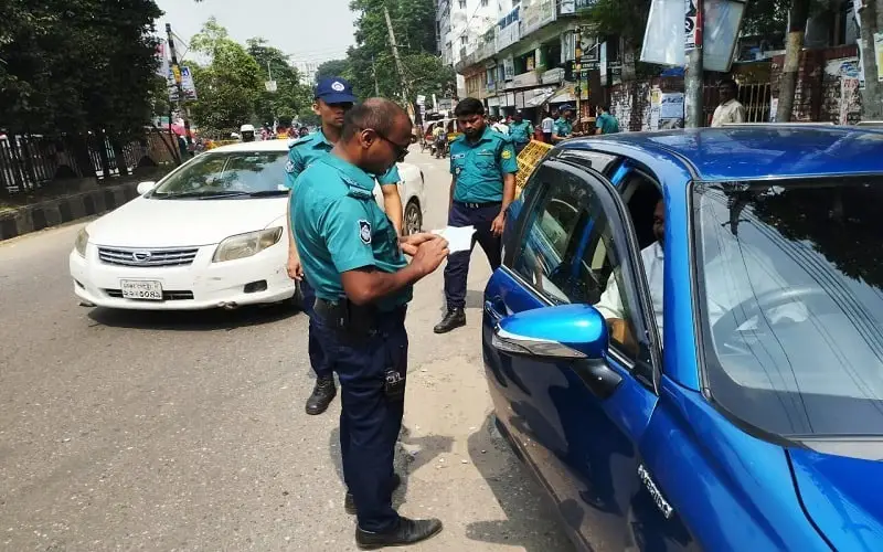 Bangladeshi traffic police officers checking a blue car on the street. Channel i News - চ্যানেল আই নিউজ