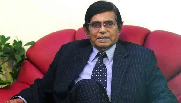 প্রখ্যাত ব্যক্তিত্ব বসে আছেন লাল সোফায়, পেছনে সবুজ গাছ. Channel i News - চ্যানেল আই নিউজ