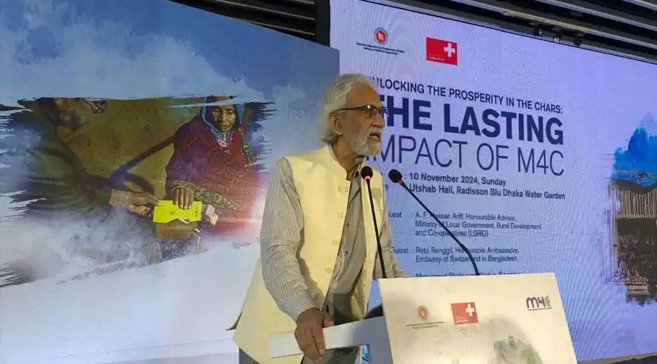 প্রধান অতিথি বক্তৃতা দিচ্ছেন, পেছনে প্রেজেন্টেশন স্লাইড দেখানো হচ্ছে. Channel i News - চ্যানেল আই নিউজ