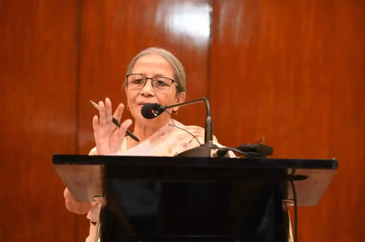 প্রধান বক্তা মঞ্চে দাঁড়িয়ে বক্তৃতা দিচ্ছেন, পেছনে গা dark brown প্যানেল. Channel i News - চ্যানেল আই নিউজ