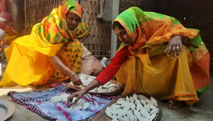 নবান্নের জন্য ধান ও পিঠা প্রস্তুত করছেন দুই নারী. Channel i News - চ্যানেল আই নিউজ