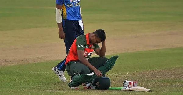 Bangladeshi cricketer sitting on the field with helmet and gear. Channel i News - চ্যানেল আই নিউজ