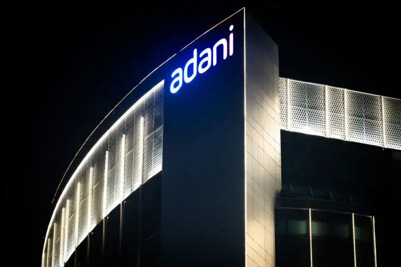 Adani logo illuminated on a modern building at night. Channel i News - চ্যানেল আই নিউজ