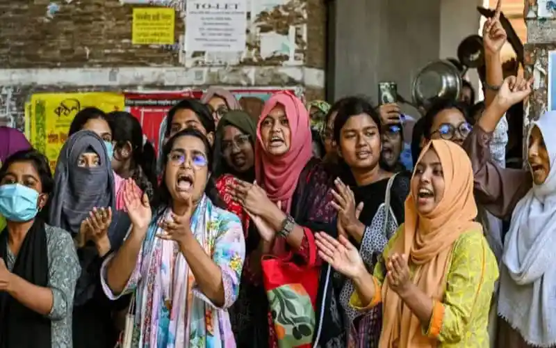 প্রার্থীরা বিক্ষোভ করছে, কিছু মুখে মাস্ক পরা, বিভিন্ন অভিব্যক্তি দেখাচ্ছে. Channel i News - চ্যানেল আই নিউজ