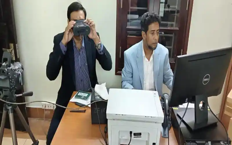 দূতাবাসে দুই ব্যক্তি ই-পাসপোর্ট সেবা পর্যবেক্ষণ করছে. Channel i News - চ্যানেল আই নিউজ