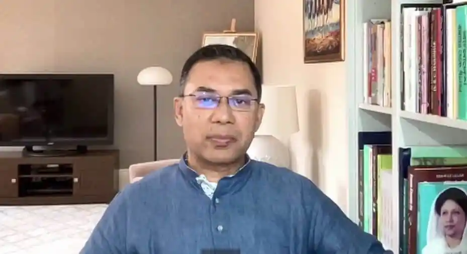 একজন ব্যক্তি ক্যামেরার সামনে বসে থাকছেন, বাড়ির অভ্যন্তরে. Channel i News - চ্যানেল আই নিউজ