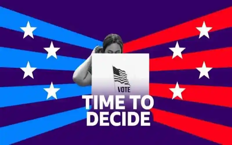Person holding a voting ballot with American flag design and 'Vote' text. Channel i News - চ্যানেল আই নিউজ