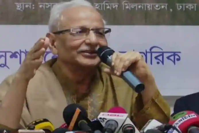 বাংলাদেশের একজন প্রবীণ ব্যক্তি বক্তৃতা দিচ্ছেন, পেছনে সংবাদ সম্মেলনের ব্যাকড্রপ।. Channel i News - চ্যানেল আই নিউজ