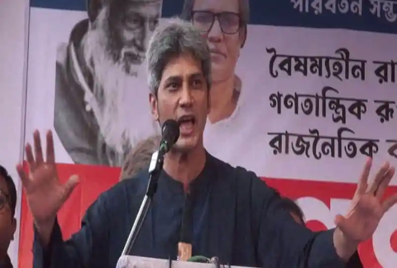 জনসভায় বক্তা ভাষণ দিচ্ছেন, পেছনে নেতাদের ছবি ও ব্যানার. Channel i News - চ্যানেল আই নিউজ