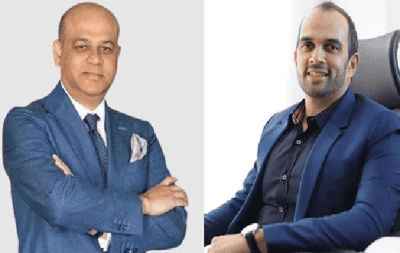 দুই ব্যক্তি পেশাদার পোশাকে, একজন বসে অন্যজন দাঁড়িয়ে. Channel i News - চ্যানেল আই নিউজ
