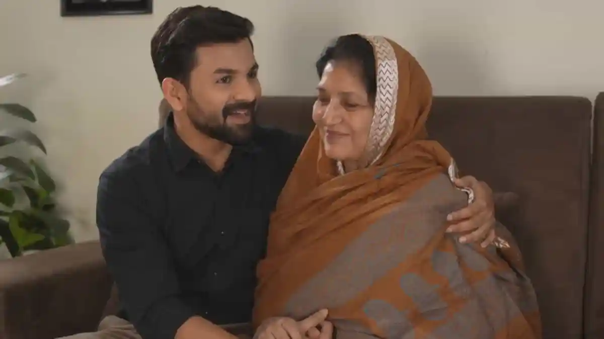 একজন যুবক ও বৃদ্ধা মা একসঙ্গে বসে হাসিমুখে আলিঙ্গন করছে।. Channel i News - চ্যানেল আই নিউজ