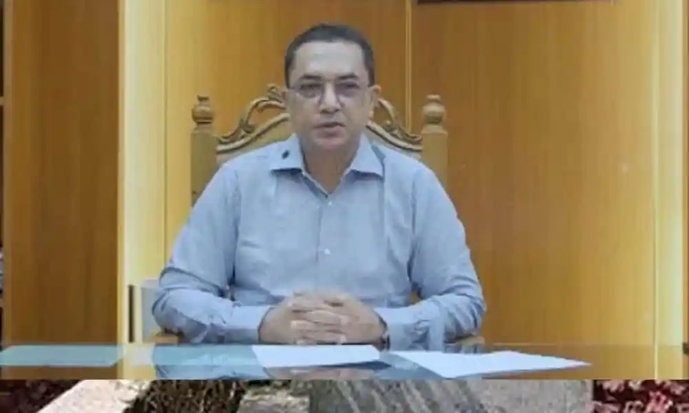 সাবেক স্বাস্থ্যসচিব জাহাঙ্গীর আলমের ছবি, বসে আছেন, পটভূমিতে কাঠের দেয়াল. Channel i News - চ্যানেল আই নিউজ