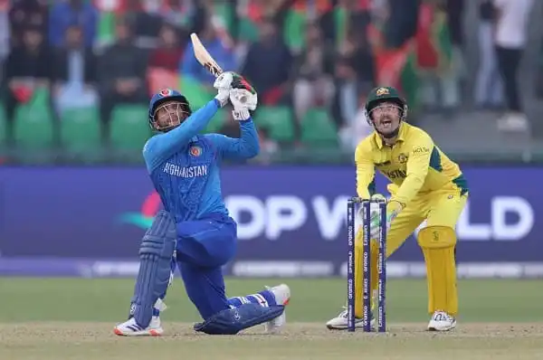 ক্রিকেট ম্যাচে আফগান ক্রিকেটার ব্যাটিং করছেন, অস্ট্রেলিয়া দলের খেলোয়াড় পাশে. Channel i News - চ্যানেল আই নিউজ