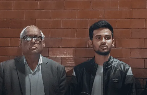 দুই ব্যক্তি আলোচনা করছেন, একজন বৃদ্ধ ও একজন যুবক, ব্রাউন ইটের দেয়ালে দাঁড়িয়ে. Channel i News - চ্যানেল আই নিউজ