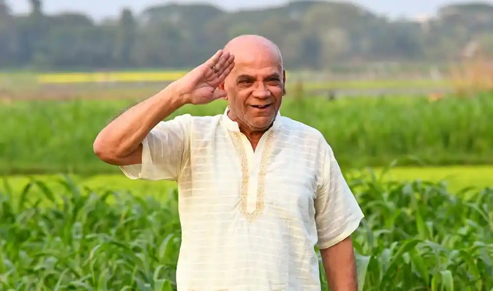 বয়স্ক ব্যক্তি কৃষিক্ষেত্রে স্বাগত জানাচ্ছেন, হাসিমুখে হাত তুলে. Channel i News - চ্যানেল আই নিউজ