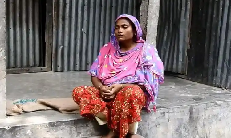একজন নারী বসে আছেন, পেছনে ধাতব চাদর দিয়ে তৈরি দেয়াল. Channel i News - চ্যানেল আই নিউজ