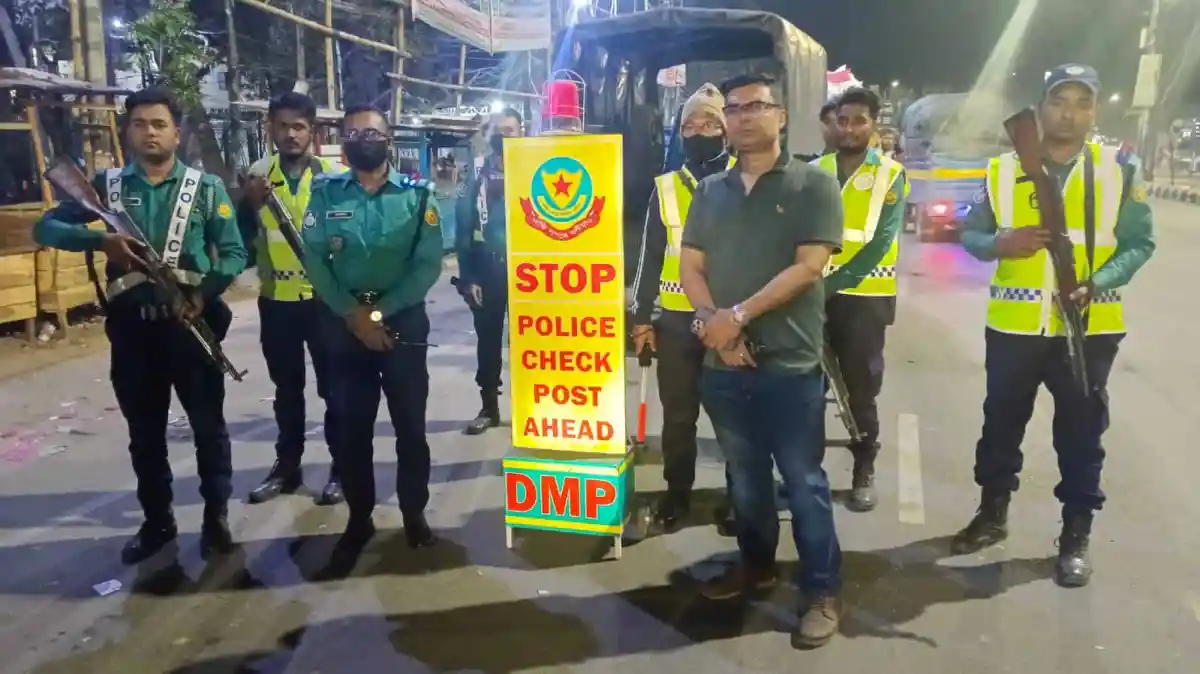 পুলিশ সদস্যরা চেকপোস্টে দাঁড়িয়ে থাকছেন, ডিএমপি ব্যানার দেখা যাচ্ছে. Channel i News - চ্যানেল আই নিউজ
