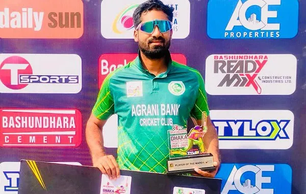 ক্রিকেট খেলোয়াড় অগ্রণী ব্যাংক ক্রিকেট ক্লাবের জার্সি পরিহিত, ট্রফি হাতে, sunglasses পরা।. Channel i News - চ্যানেল আই নিউজ