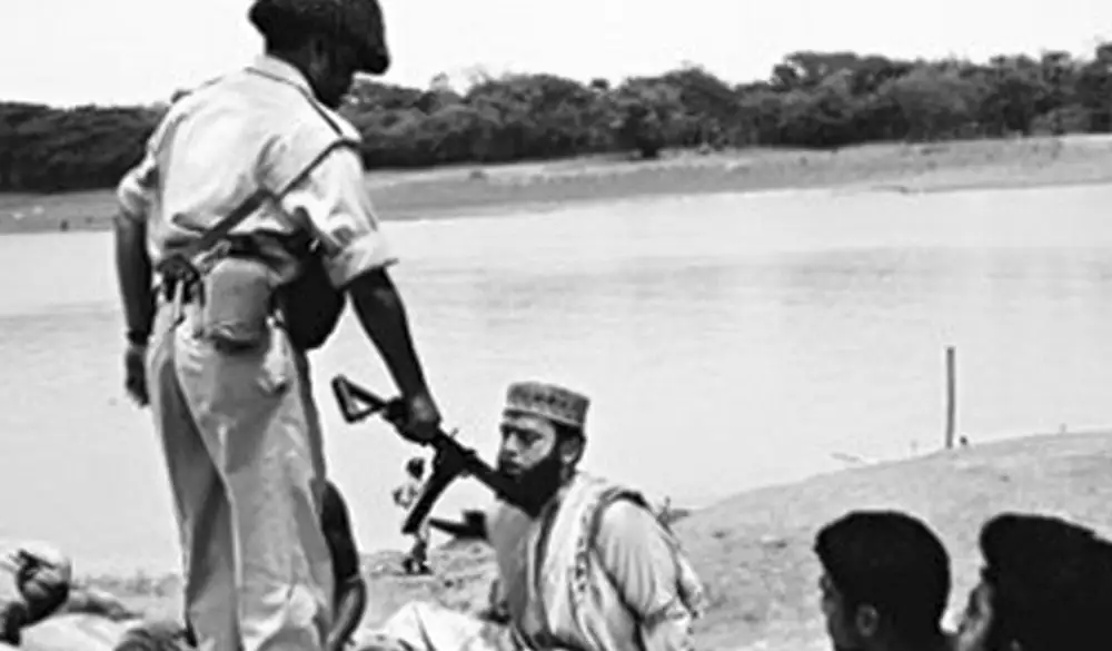 যুদ্ধের সময় একজন সৈনিক অস্ত্র হাতে অন্যদের সঙ্গে আলোচনা করছে. Channel i News - চ্যানেল আই নিউজ