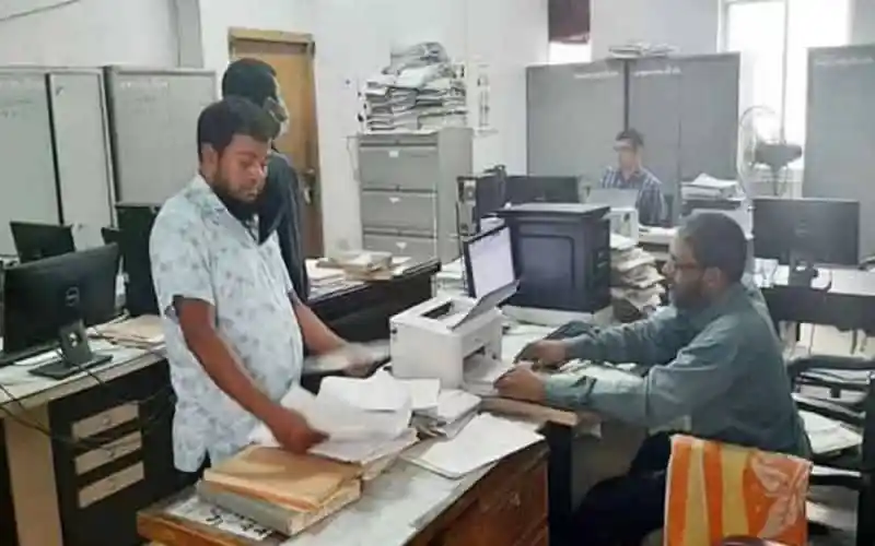 অফিসে কর্মীরা কাজ করছেন, কাগজপত্র ও কম্পিউটার ব্যবহৃত হচ্ছে. Channel i News - চ্যানেল আই নিউজ