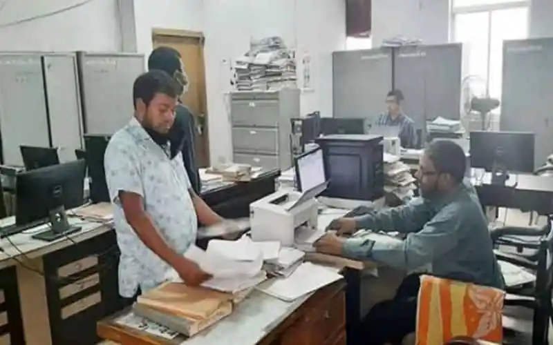 সরকারি অফিসে কর্মরত কর্মীরা কাজ করছেন, পত্রপত্রিকা ও ডকুমেন্ট দেখছেন. Channel i News - চ্যানেল আই নিউজ