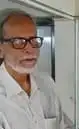 বাংলাদেশের একজন প্রবীণ ব্যক্তি, চশমা পরা, পটভূমিতে আধুনিক অফিস পরিবেশ. Channel i News - চ্যানেল আই নিউজ
