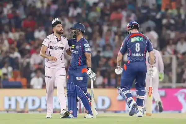 ক্রিকেট খেলোয়াড়রা মাঠে আলোচনা করছে, দর্শকরা স্ট্যান্ডে দেখছেন. Channel i News - চ্যানেল আই নিউজ