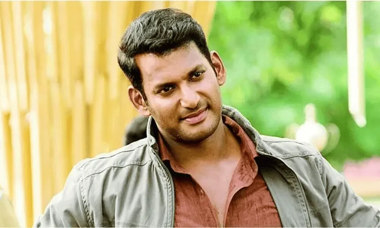 Smiling young man outdoors with green background and bamboo fencing. Channel i News - চ্যানেল আই নিউজ