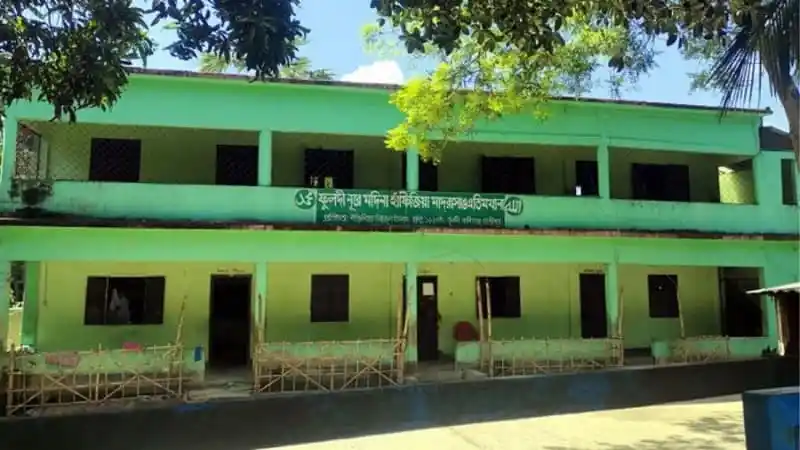 সবুজ রঙের মাদ্রাসা ভবন, ছাদে কিছু গাছ ও জানালা. Channel i News - চ্যানেল আই নিউজ