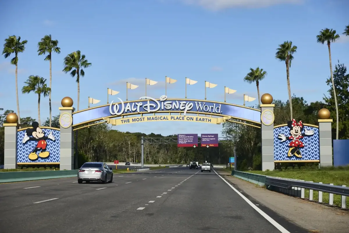 Walt Disney World entrance with Mickey Mouse images and flags, sunny day. Channel i News - চ্যানেল আই নিউজ
