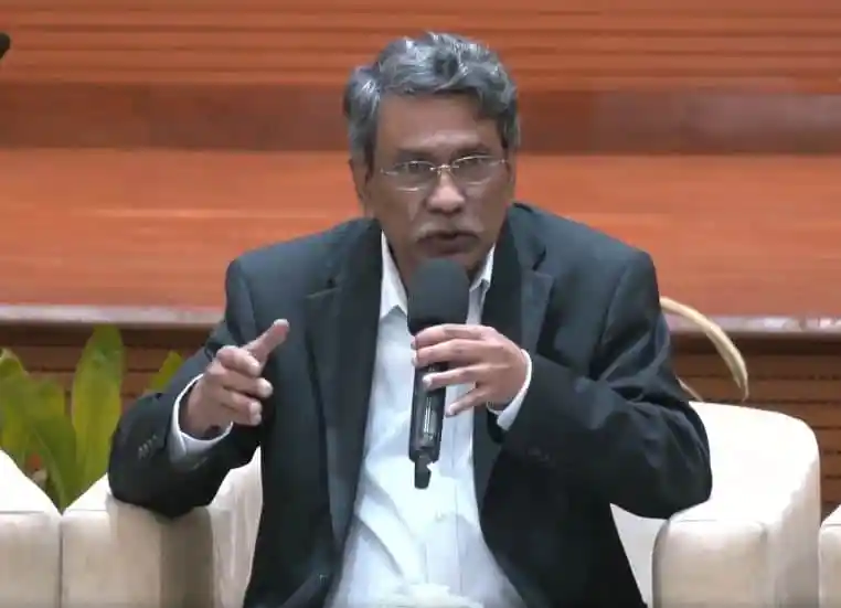 আলী রীয়াজ বক্তৃতা দিচ্ছেন, পেছনে গাছ ও কাঠের দেয়াল. Channel i News - চ্যানেল আই নিউজ