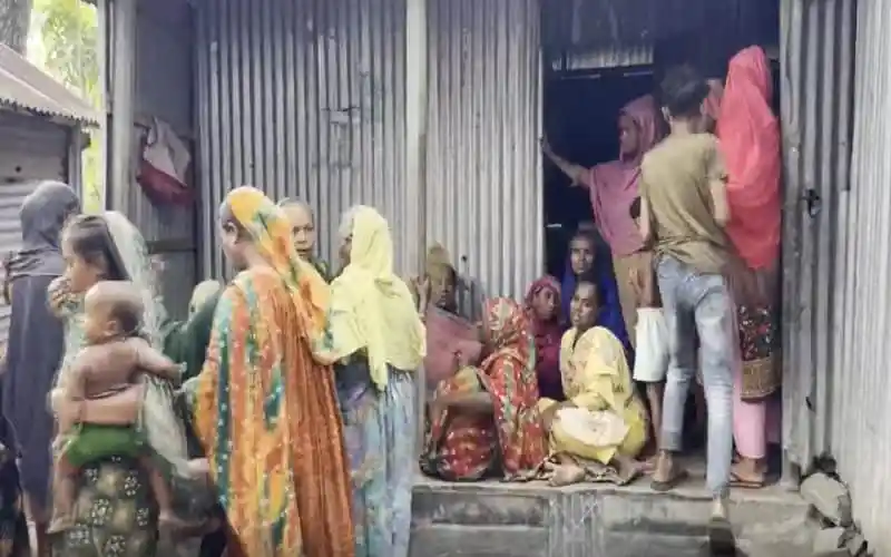 বস্তিতে অনেক মানুষ একত্রে বসে আলোচনা করছে. Channel i News - চ্যানেল আই নিউজ