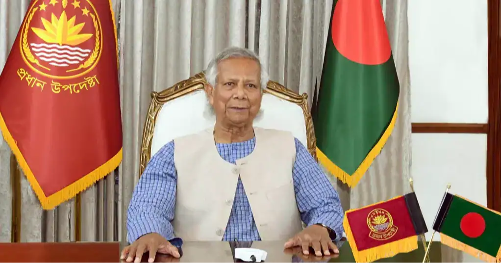 প্রধান উপদেষ্টা বসে আছেন, পেছনে বাংলাদেশের পতাকা ও চ্যানেল আই লোগো. Channel i News - চ্যানেল আই নিউজ